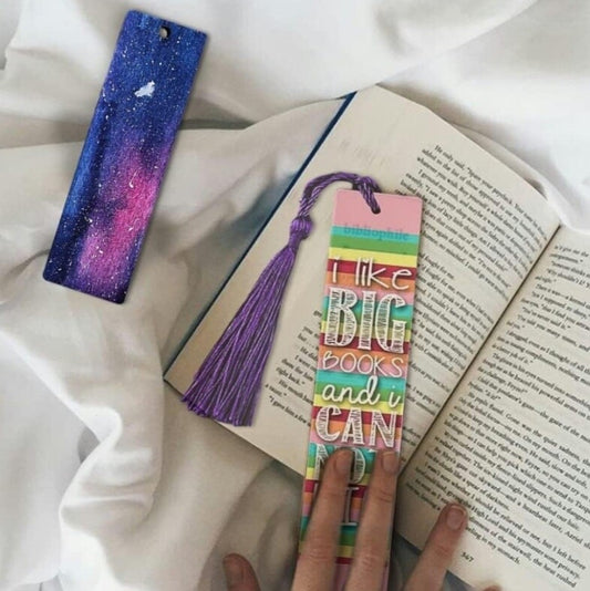 Colorful bookmark with text held over an open book on a white fabric background