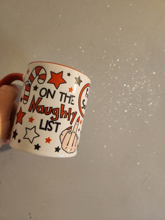 Mug with 'On the Naughty List' text and festive design held against a sparkly background