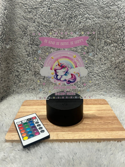 Decorative night light with unicorn design on a wooden stand, featuring a remote control with color-changing buttons.